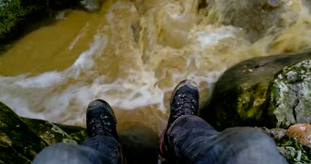 Пішохід вішає ногу над річкою зі скелі — стокове відео