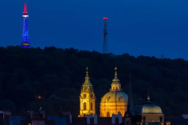 Iglesia de San Nicolás con torre de vigilancia Petrin detrás en la noche — Foto de Stock