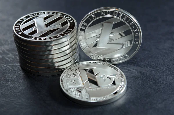 Coluna de litecoins com duas moedas ao lado deles na superfície de couro escuro. Conceito de criptomoeda virtual . — Fotografia de Stock