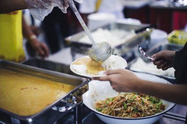 Gezginin eli bağışlardan yiyecek alabilmek için uzanıyor. Gönüllüler yiyecek toplarken: Açlığa yardım etme fikri
