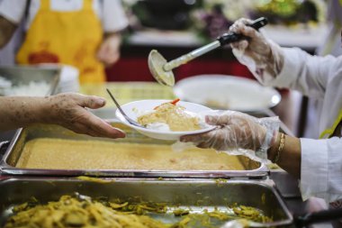 Gezginin eli bağışlardan yiyecek alabilmek için uzanıyor. Gönüllüler yiyecek toplarken: Açlığa yardım etme fikri