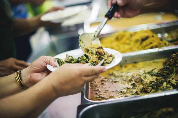 Warm food scooped from ladle into a container of the poor: the concept of giving