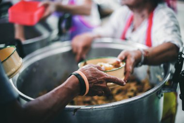 The hands of the poor apply for food from rich people who donate food.