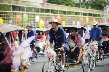 CHIANG MAI, THAILAND - FEBRUARY 08, 2020: Cyclists take tourists to the parade at the 44th flower festival parade in Chiang Mai, Thailand