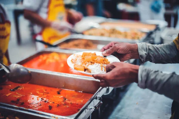 Volunteers serving food for poor people : concept of free food serving