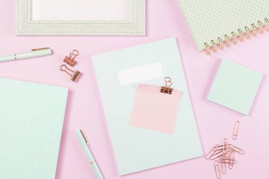  Pembe pastel arka planda çalışma masasının üzerine yaslanmış kırtasiye malzemesi