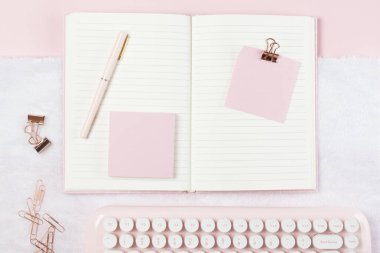 Pembe pastel arka planda çalışma masasının üzerine yaslanmış kırtasiye malzemesi