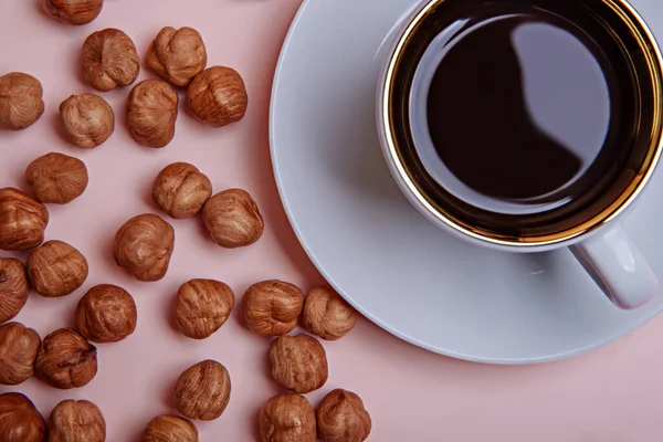 Bir fincan kahve espresso ve soyulmuş fındık..