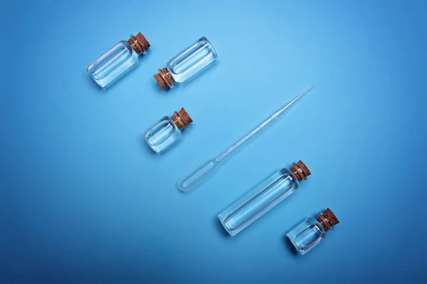 Small bottles with oil and dropper on blue background.