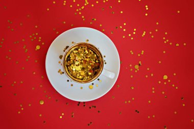 Kırmızı arka planda küçük bir fincanda altın parıldıyor..