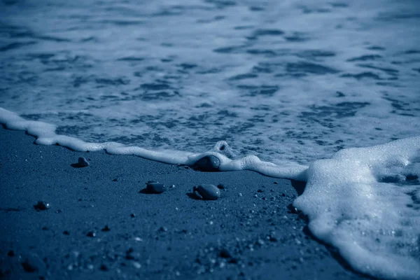Волновой серфинг. Камни на берегу моря в модном классическом синем тоне . — стоковое фото