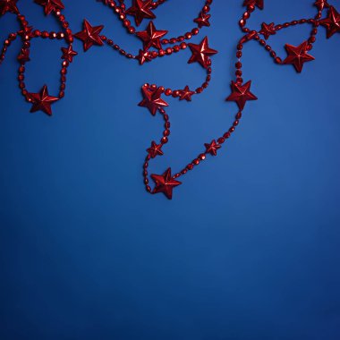 Mavi arka planda yıldızlı kırmızı Noel boncukları.