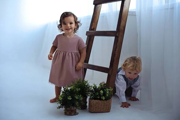 Malý chlapec a dívka hrají v blízkosti dřevěných schodů v světlé místnosti. — Stock fotografie