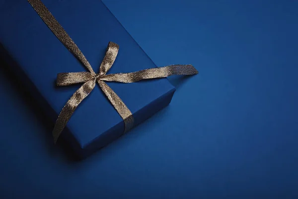 Caixa de presente embrulhado em papel azul clássico com uma fita de ouro . — Fotografia de Stock