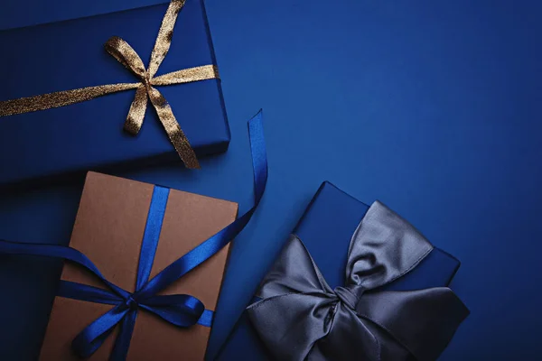 Caixas de presente embrulhadas em papel azul clássico com fitas douradas, azuis e cinzentas . — Fotografia de Stock