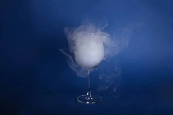 Large wine glasses with smoke on a blue background.