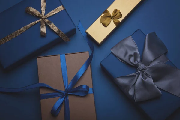 Caixas de presente embrulhadas em papel azul clássico com fitas douradas, azuis e cinzentas . — Fotografia de Stock