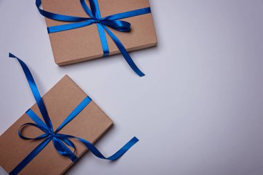 Two gift boxes wrapped in craft paper with a classic blue ribbons.