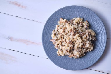 Gri tabakta yakın plan mantarlı risotto. Beyaz ahşap bir masada İtalyan yemeği.