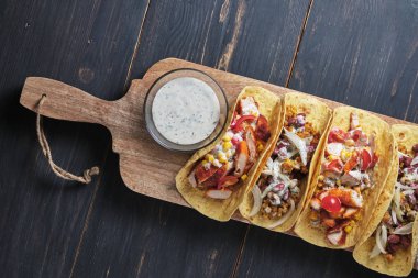 Eski ahşap bir masada etli ve sebzeli Meksika tacoları. Öğle ve akşam yemeği için hızlı sokak yemekleri.