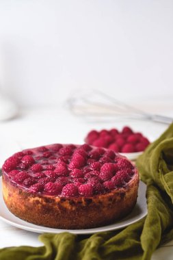 Ahududulu cheesecake ile sabah kahvaltısı. Beyaz ahşap bir masada tatlı ve ahududu..