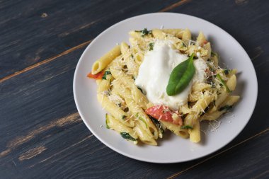 Domatesli makarna, ıspanak, parmesan ve bolonez soslu. Ahşap bir masada tabakta servis yapmak..