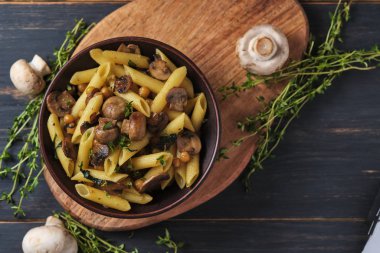 Mantarlı vejetaryen makarna, nohut, ıspanak, baharat ve otlar. Eski ahşap bir masada kasede İtalyan makarnası. Üst görünüm.