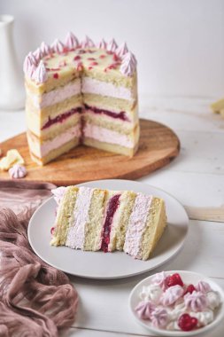 Beyaz bir masanın üzerinde beyaz çikolata ve kirazlı kek. Bir tabakta dilimlenmiş kek ve bir fincan espresso. Ev yapımı şekerlemelerle süslenmiş tatlı.