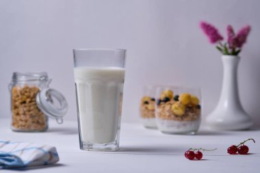 Bir bardak süt ve yoğurtlu granola ve taze böğürtlen. Beyaz ahşap masada kahvaltı..