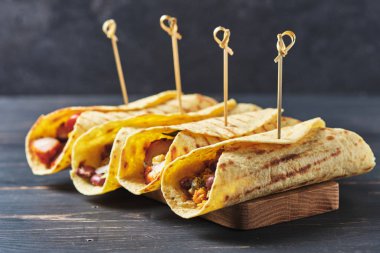 Eski ahşap bir masada etli ve sebzeli Meksika tacoları. Öğle ve akşam yemeği için hızlı sokak yemekleri.