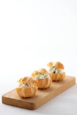 Yumuşak peynirli profiteroller, kırmızı balıklar ve otlar. Tatil masası için gurme yemeği..