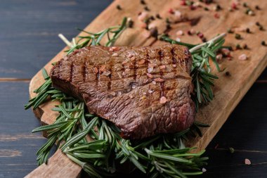 Biberiye dallarında taze pişmiş biftek. Tabak büyük bir tahta üzerinde servis edilir. Yakın plan..