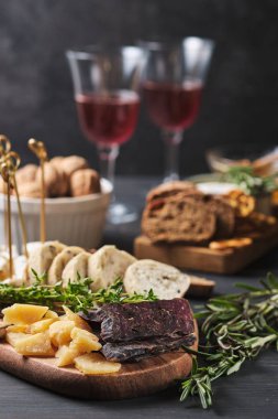 Delicious snacks and wine. Several varieties of cheese, nuts, ciabatta and sausage on an old wooden table. Food for a romantic dinner. clipart