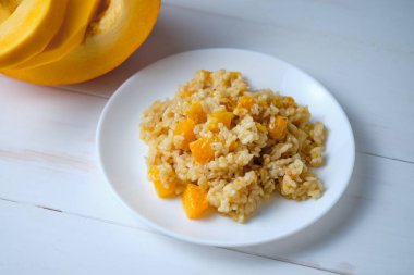 Balkabağı kapaklı risotto. Beyaz masada İtalyan yemeği..