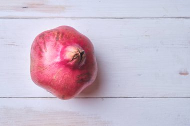 Beyaz ahşap bir masada nar. Metin için yer.