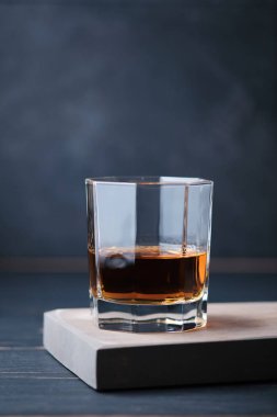 Bardaki tahta bir tahtanın üzerinde bir bardak viski. Alkollü içeceklerle dolu bir bar tezgahı.