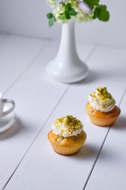 Kahvaltı için kahve ve meyveli kek. Sabah masasında tatlı, espresso ve beyaz ahşap bir masada vazoda çiçekler..