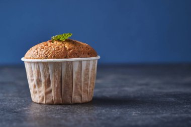 Masada nane şekeriyle süslenmiş haşhaşlı limonlu kek. Arkaplan rengi klasik mavi.