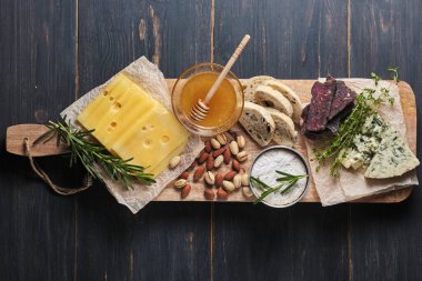 Farklı peynir türleri tatmak, bal, fındık, otlar, ciabatta ve sosis. Tahta üzerinde çeşitli peynir çeşitleri var. Romantik bir akşam yemeği için şarküteriler. Yukarıdan görüntüle.