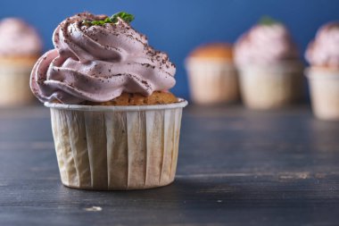 Pembe kremalı tatil kekleri. Tatlı nane yaprakları ve çikolata parçacıklarıyla süslenmiş. Arkaplan rengi klasik mavi.