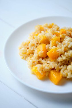 Balkabağı kapaklı risotto. Beyaz masada İtalyan yemeği..