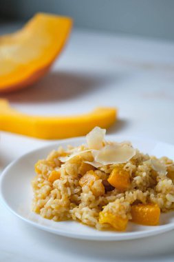 Balkabağı kapaklı risotto. Beyaz masada İtalyan yemeği..
