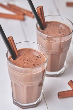 Çikolatalı milkshake, beyaz ahşap bir masada cam bardakta tarçınlı..