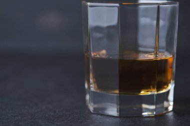 Bardaki ahşap bir masada bir bardak viski. Alkollü içeceklerle dolu bir bar tezgahı.