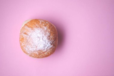 Donut, yakın plan pembe kağıt üzerine krema şekeri ile süslenmiş. Yukarıdan görüntüle.
