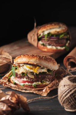 close up of mouth-watering burger with grilled beef patty and fresh vegetables. Tasty american cheeseburger on wooden board. 