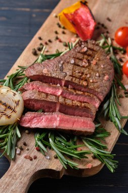 Kana bulanmış taze biftek ızgara sebze ve ahşap bir tahtanın üzerinde taze biberiye ile servis edilir. Yakın plan..