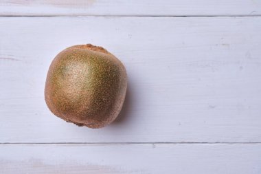 Beyaz ahşap bir masada Kivi. Metin için yer.