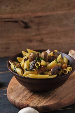 Mantarlı vejetaryen makarna, nohut, ıspanak, baharat ve otlar. Eski ahşap bir masada kasede İtalyan makarnası..