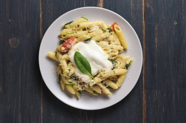 Domatesli makarna, ıspanak, parmesan ve bolonez soslu. Ahşap bir masada servis tabağı. Üst görünüm.